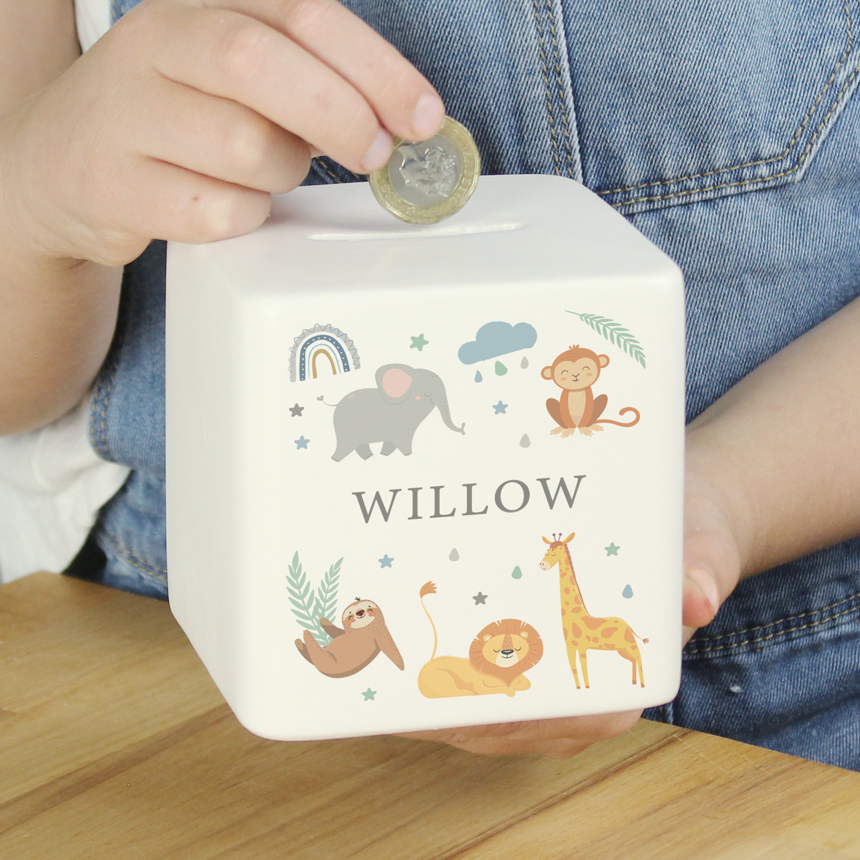 A white ceramic square money box with a personalised name 'Arthur' and a jungle animal theme, featuring illustrations of an elephant, giraffe, monkey, lion, and zebra.