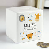 A white ceramic square money box with a personalised inscription and decorated with safari animal illustrations, including a lion and a giraffe, and the name 'Noah'.