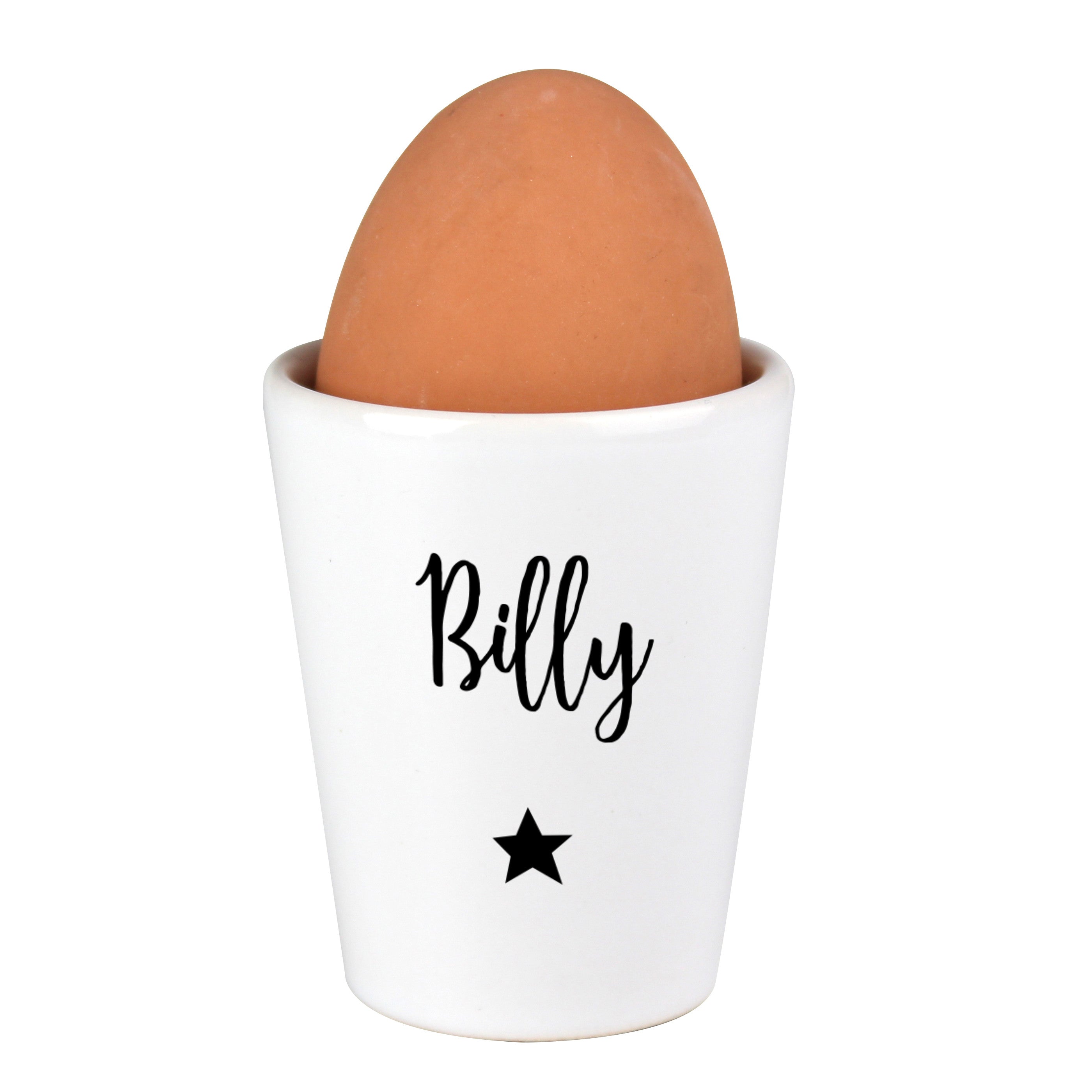 A white ceramic egg cup with the name 'Stanley' printed on it, alongside a spoon and a piece of toast, with an egg placed in the egg cup.