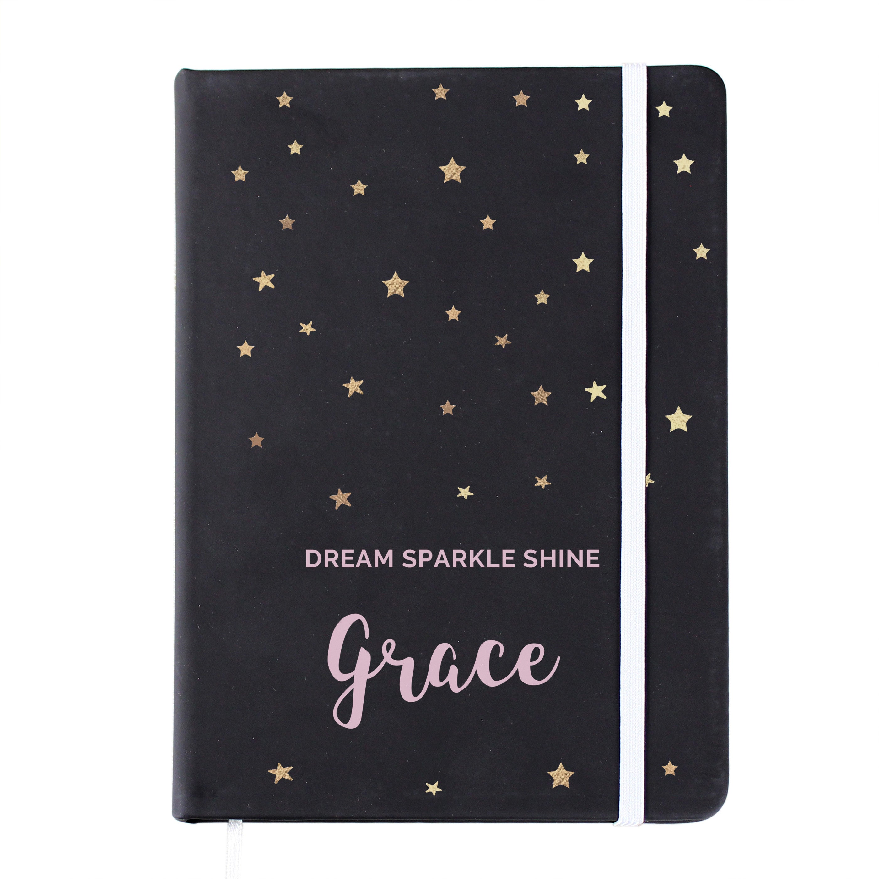 A personalised black hardback notebook with star patterns on the cover, held in a hand, with a mobile phone and a plant in the background.