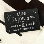 A black wallet card with white text saying 'Daddy I love you to the moon & back - Love from Arthur X', held against a brown wallet background.