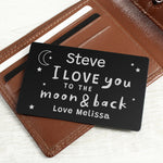A black wallet card with white text saying 'Daddy I love you to the moon & back - Love from Arthur X', held against a brown wallet background.