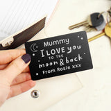 A black wallet card with white text saying 'Daddy I love you to the moon & back - Love from Arthur X', held against a brown wallet background.