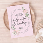 A personalised voucher card with floral design and the text 'This token entitles you to breakfast in bed' along with the name 'Amelia'. The card is displayed on a wooden surface with a round brown plate behind it. 01