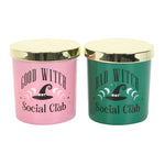Two candles with gold lids, one pink and one green, featuring 'Good Witch Social Club' and 'Bad Witch Social Club' text.