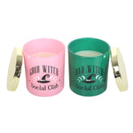 Two candles in pink and green containers with 'Good Witch Social Club' and 'Bad Witch Social Club' text.