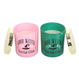 Two candles in pink and green containers with 'Good Witch Social Club' and 'Bad Witch Social Club' text.
