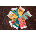 A child holding a scavenger hunt card with a rainbow and a red apple on it, in front of a blue background.