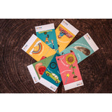 A child holding a scavenger hunt card with a rainbow and a red apple on it, in front of a blue background.