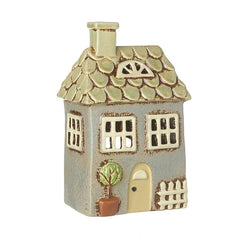 A ceramic house-shaped T-light holder with a neutral green color and a beech tree design outside the door.