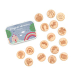 A collection of wooden story tokens with fairytale themed engravings, placed on a marble surface with a person's hand reaching out to pick up a token.