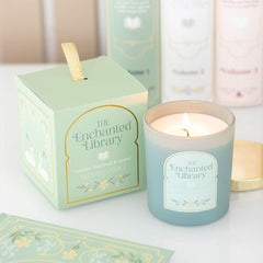 Candle with 'The Enchanted Library' branding and packaging on a light background