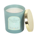Candle in a teal container with a gold lid labeled 'The Enchanted Library' on a white background