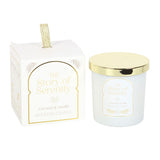 Scented candle with gold lid and packaging labeled 'The Story of Serenity' on a white background