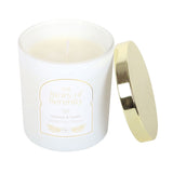 White candle with gold lid and 'The Story of Serenity' label on a white background