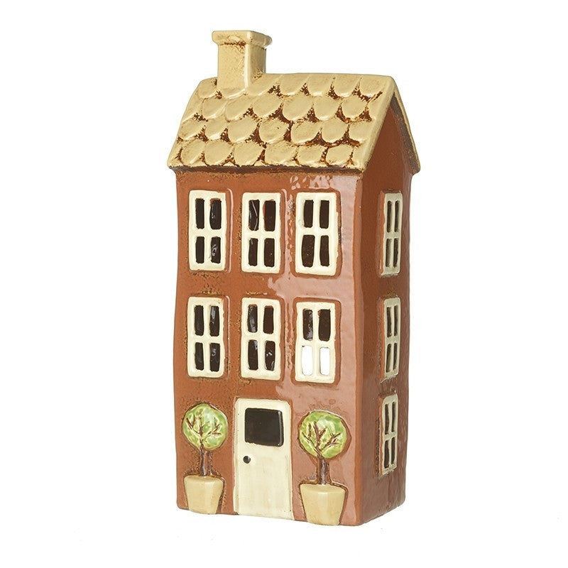 holder in the shape of a tall brown house with white windows and a gold roof.