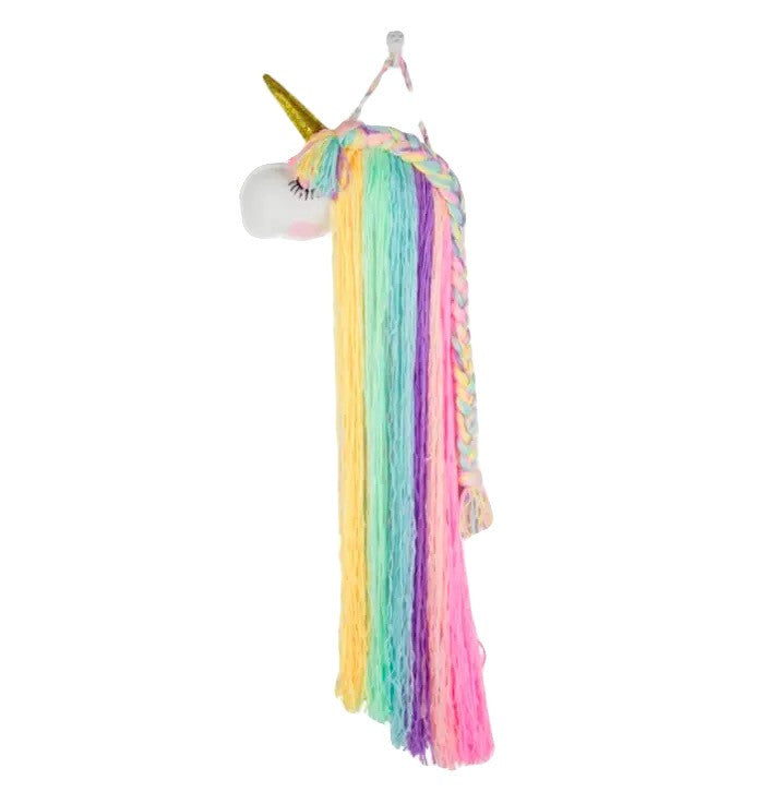 A colourful unicorn wall hanging decoration with a blue background, hanging over a wooden cabinet with a mug and a coffee pot on it.