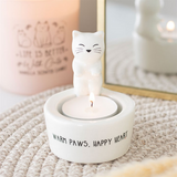 Ceramic cat-shaped candle holder with a lit candle on a textured surface.