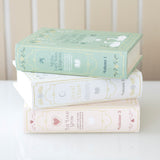 Stack of decorative books with pastel covers on a white surface