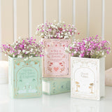 Three decorative planters filled with pink and white flowers, each on top of a book with text.