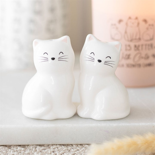 Two white cat-shaped night lights on a surface with a blurred background