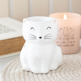 White cat-shaped night light with a candle in the background