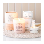 Candle with cat-themed design and decorative cat figurines on a textured surface.